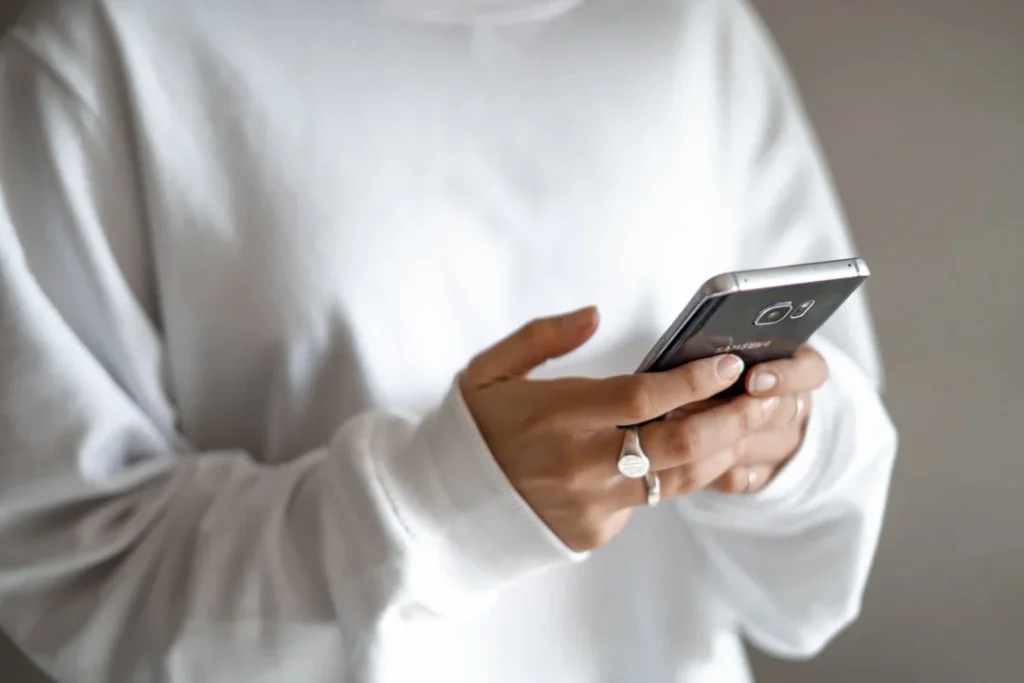 Young woman texting on her smartphone, illustrating the ATM slang meaning in text messages