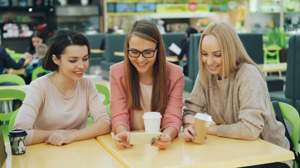 Friends laughing while reading a text message together, illustrating the JS slang meaning in texting