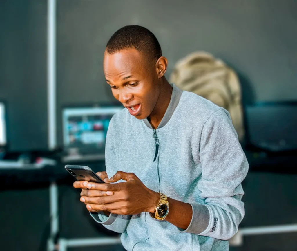 Person reacting with excitement while looking at their phone, illustrating the gyat meaning as an exclamation of shock or admiration